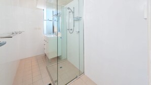 Un baño moderno con ducha envuelta en vidrio, un lavamanos y un espejo.