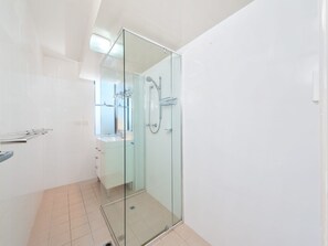 Een moderne badkamer met een douchecabine van glas, een wastafel en een spiegel.