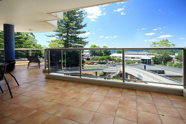 A balcony with a clear view of a parking area and a bridge.