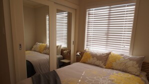 A bedroom with a bed, a nightstand, a mirror, and a window with blinds. - Pollys' View Nelson Bay Water View Family Home (Nelson Bay)