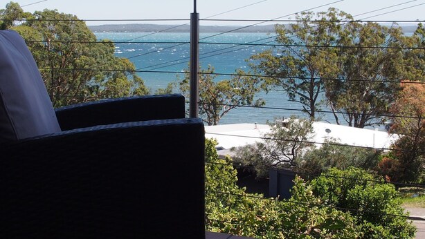 Ein Balkon mit Blick auf das Meer und die umliegenden Bäume.