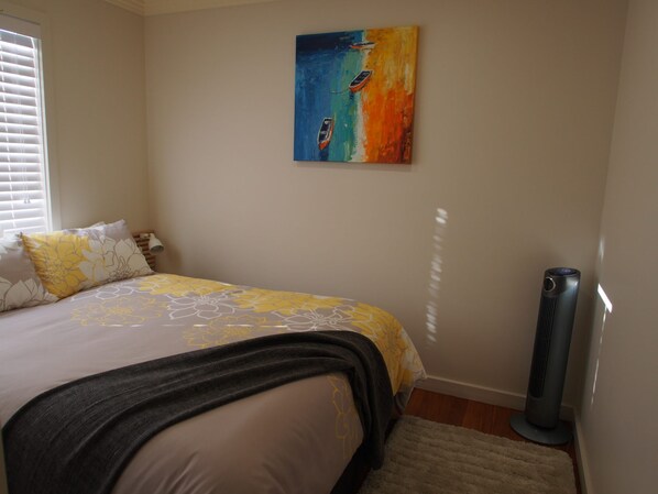 A bedroom with a bed, a painting on the wall, and a standing heater. - Pollys' View Nelson Bay Water View Family Home (Nelson Bay)