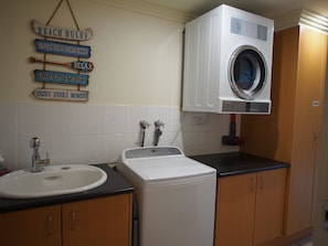 A laundry area with a washing machine, a sink, and a wall-mounted drying rack. - Pollys' View Nelson Bay Water View Family Home (Nelson Bay)