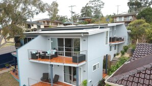 A modern two-story house with a balcony, large windows, and a flat roof. - Pollys' View Nelson Bay Water View Family Home (Nelson Bay)