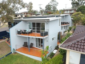 Een modern herenhuis met balkon, grote ramen en een plat dak.