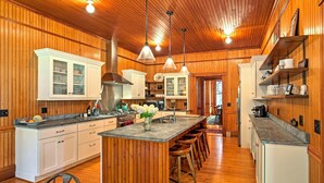 Una cocina amplia con paneles de madera, una isla central con taburetes e iluminación colgante.