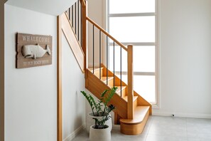 A wooden staircase with a sign above it, a potted plant, and a window with natural light. - Signature House Family Retreat Corlette (Corlette)