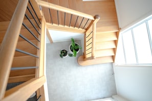 A wooden staircase with a handrail, leading to a landing with two potted plants. - Signature House Family Retreat Corlette (Corlette)