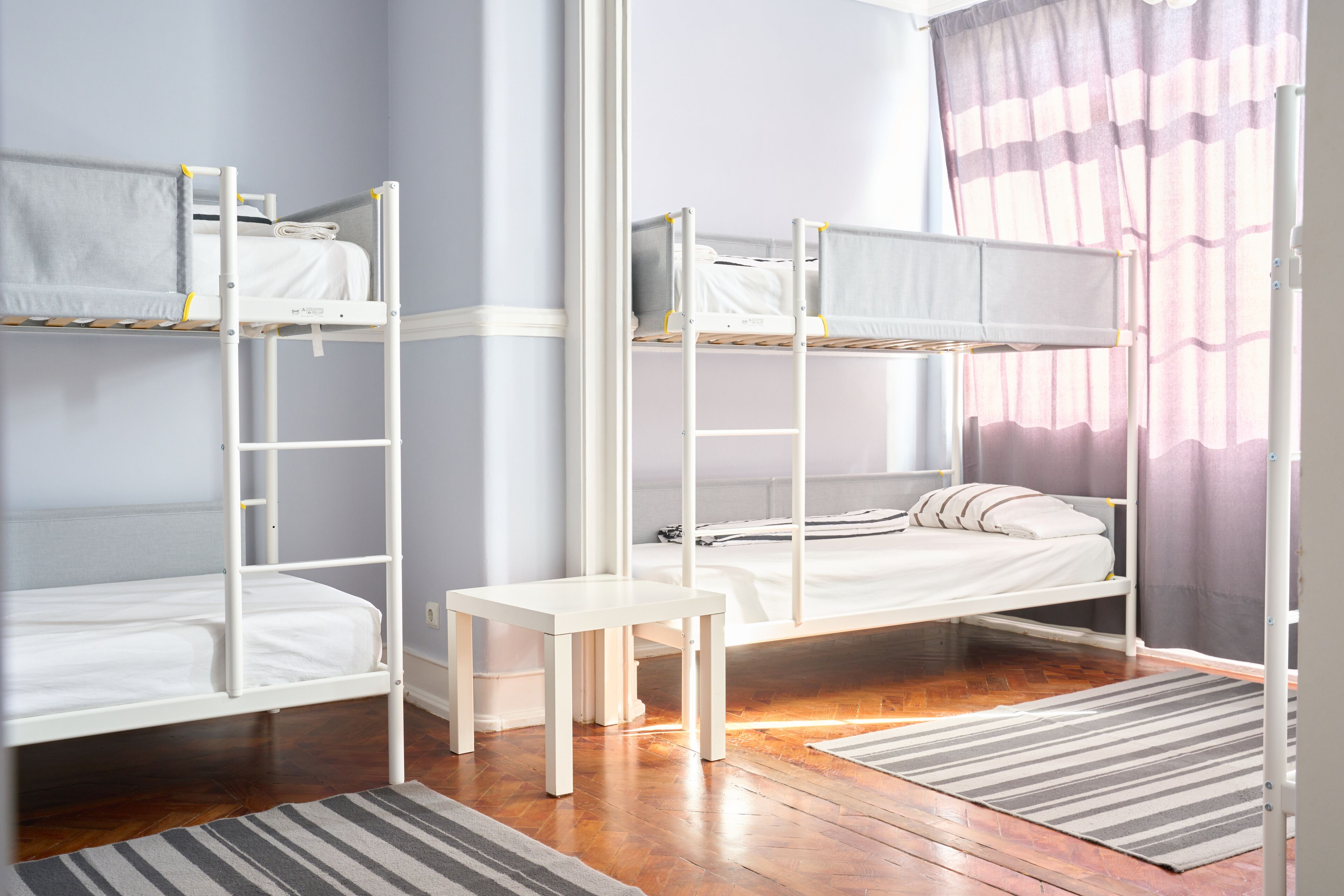 Habitación con literas, una pequeña mesa y un tapete a rayas.
