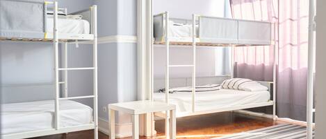 Habitación con literas, una pequeña mesa y un tapete a rayas.