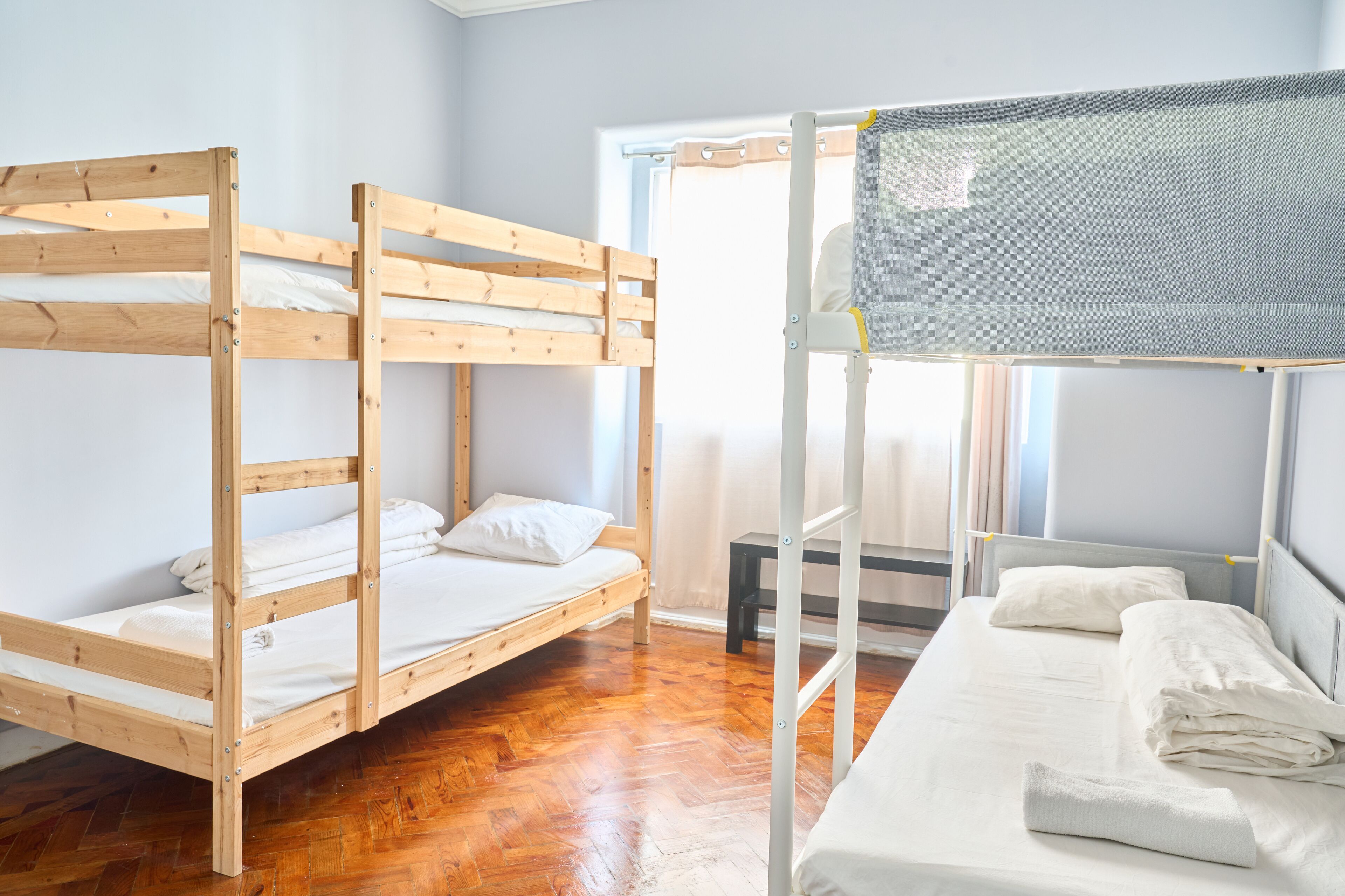 Une chambre de dortoir avec deux lits superposés, une petite table et une fenêtre avec des rideaux.