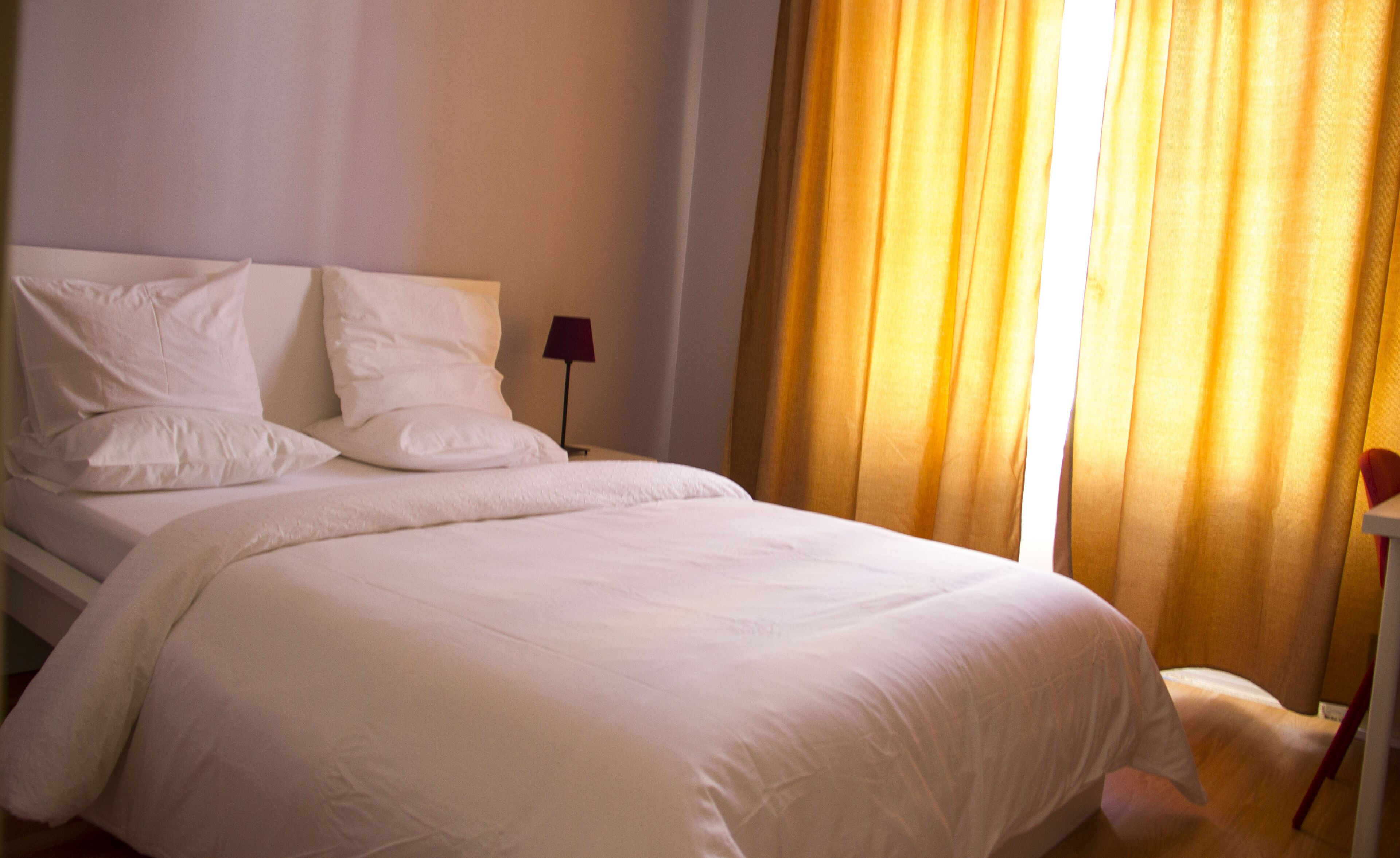 A neatly made bed with white linens in a hotel room.