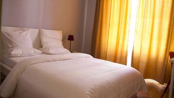 A neatly made bed with white linens in a hotel room.