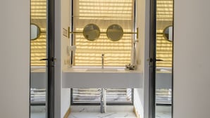 A modern bathroom with a large window, a sink, and two round mirrors. - Folk Boutique Hotel (Tbilisi)