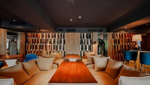 A modern living room with a central wooden coffee table, leather sofas, and a large wine rack filled with bottles. - Folk Boutique Hotel (Tbilisi)