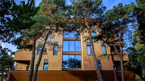 A modern building with a wooden facade, large windows, and surrounded by trees. - Folk Boutique Hotel (Tbilisi)