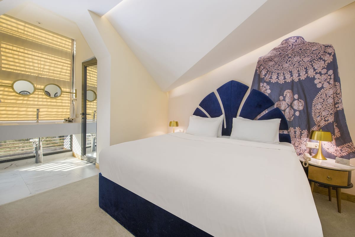 Une chambre d’hôtel moderne dotée d’un grand lit, d’un balcon avec une rambarde et offrant une vue sur l’extérieur.