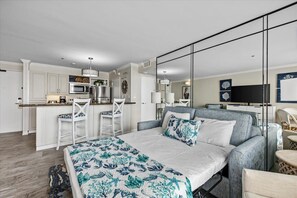 Une chambre d’hôtel moderne dotée d’un grand lit, d’une kitchenette, d’un coin repas et d’une télévision.