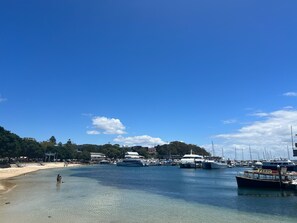 A marina with boats docked, a beach, and buildings in the background. - Foreshore Paradise Nelson Bay (Nelson Bay)