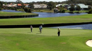 A golf course with a water hazard, a putting green, and a sand bunker.