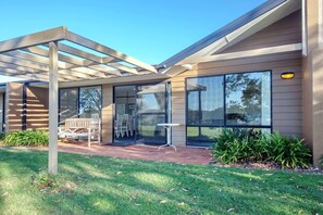 A modern house with a covered patio, large windows, and a well-maintained lawn. - Horizons Retreat Golf Front Villa Salamander Bay (Salamander Bay)