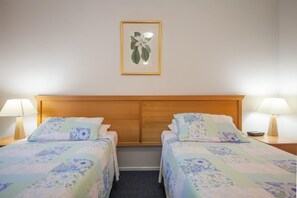 A hotel room with two single beds, a wooden headboard, and a framed botanical print on the wall. - Horizons Retreat Golf Front Villa Salamander Bay (Salamander Bay)