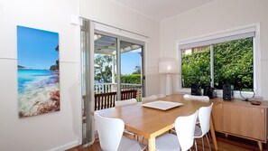 Enjoy meals in this dining area with a view of lush greenery, featuring a wooden table and comfortable seating.