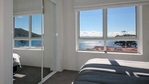 Una camera da letto con un'ampia finestra vista su un corpo d'acqua e un paesaggio collinare.