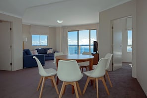 Een moderne woonkamer met een eethoek, grote ramen en uitzicht op zee.