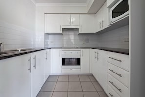 A kitchen with white cabinets, a stove, and a microwave.