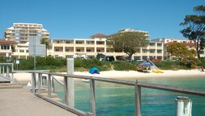 Una proprietà sul lungomare con molo di legno, spiaggia sabbiosa e un edificio con numerosi balconi.