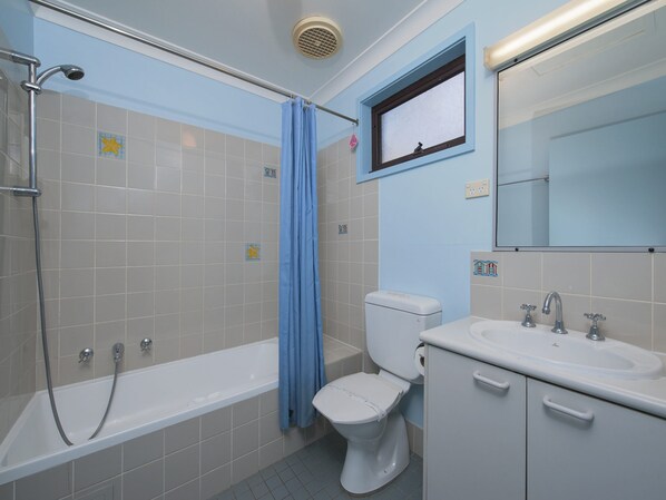 A bathroom with a bathtub, toilet, and sink.