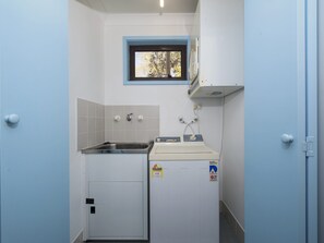 A compact kitchen with a sink, a small window, and a washing machine. - Carindale 21 Nelson Bay Apartment with Pool (Nelson Bay)
