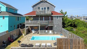 A two-story house with a backyard swimming pool, a wooden deck, and a covered patio area.