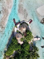 Vista aérea de un resort con un edificio circular, aguas turquesas cristalinas y exuberante vegetación.