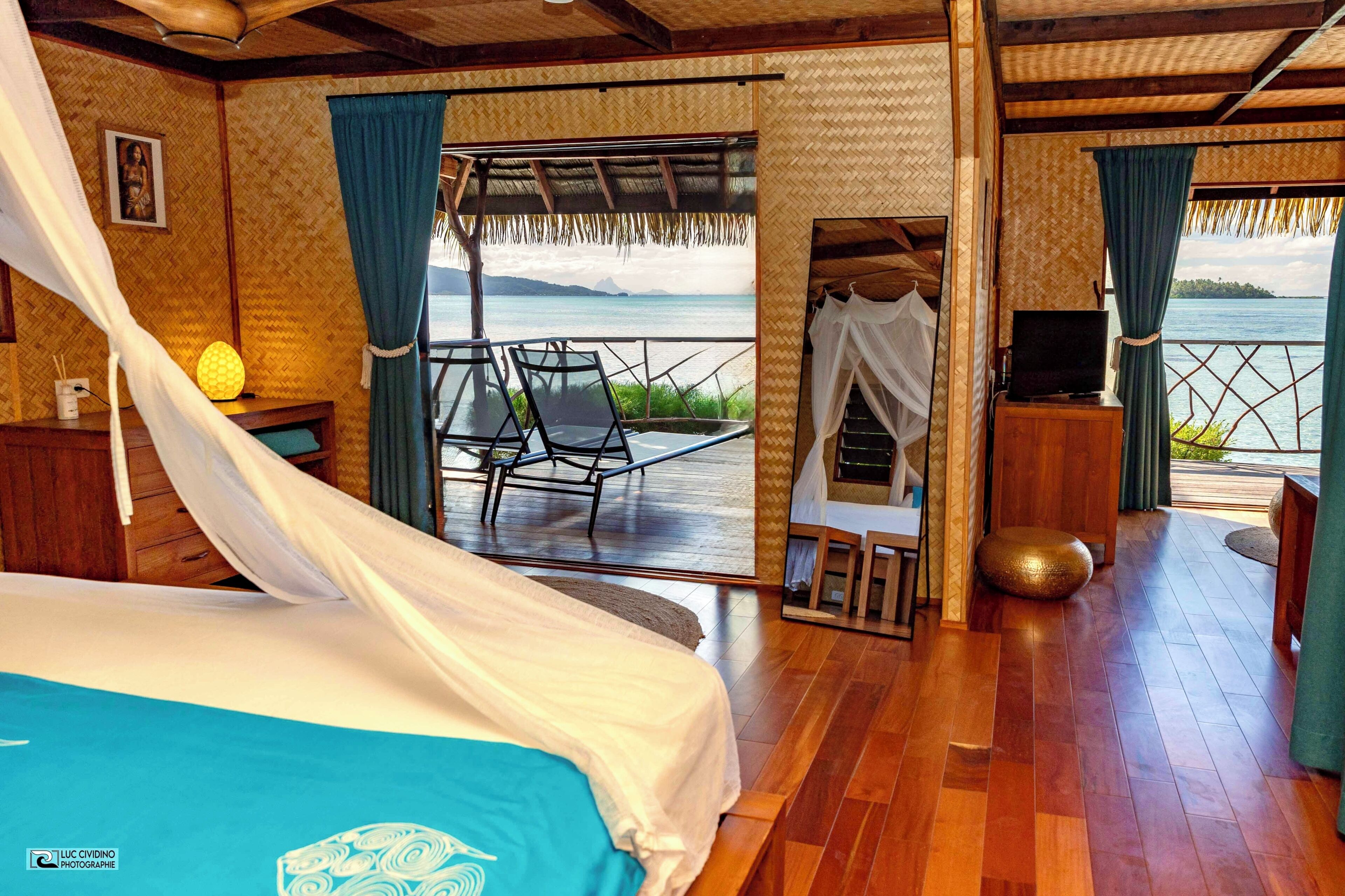 A room with a bed, a TV, and a view of the sea.