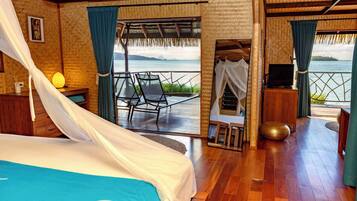 A room with a bed, a TV, and a view of the sea.