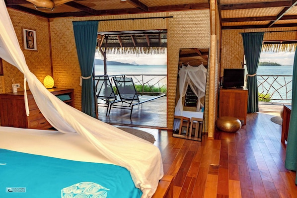 A room with a bed, a TV, and a view of the sea.