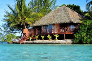 A thatched-roof bungalow with a wooden deck and a staircase leading to a covered area. - EDEN - Private Island - TAHA'A (Taha'a)