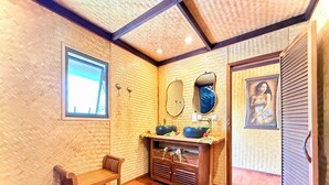 A room with a wooden floor, a wooden bench, a vanity with a mirror, a sink, and a framed picture on the wall. - EDEN - Private Island - TAHA'A (Taha'a)