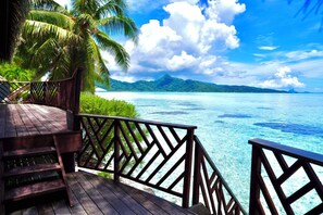 Une terrasse en bois, dotée d’une balustrade, qui offre une vue sur une mer d’un bleu limpide et un paysage tropical.