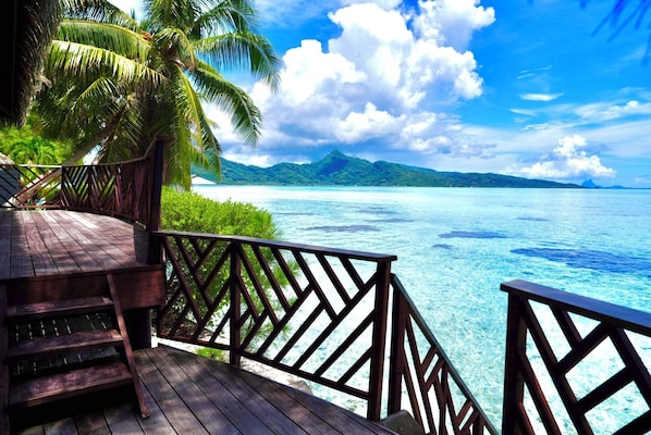 A wooden deck with a railing overlooking a clear blue sea and a tropical landscape. - EDEN - Private Island - TAHA'A (Taha'a)