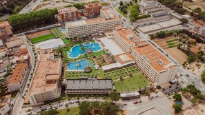 An aerial view of a hotel complex with multiple buildings, a central courtyard with pools, and surrounding greenery. - Evenia Olympic Resort - Olympic Park (Lloret de Mar)