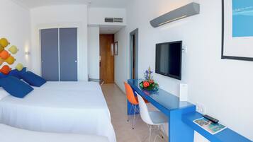Habitació d'hotel amb un llit, una taula de treball amb una cadira, una televisió i un quadre al mur.