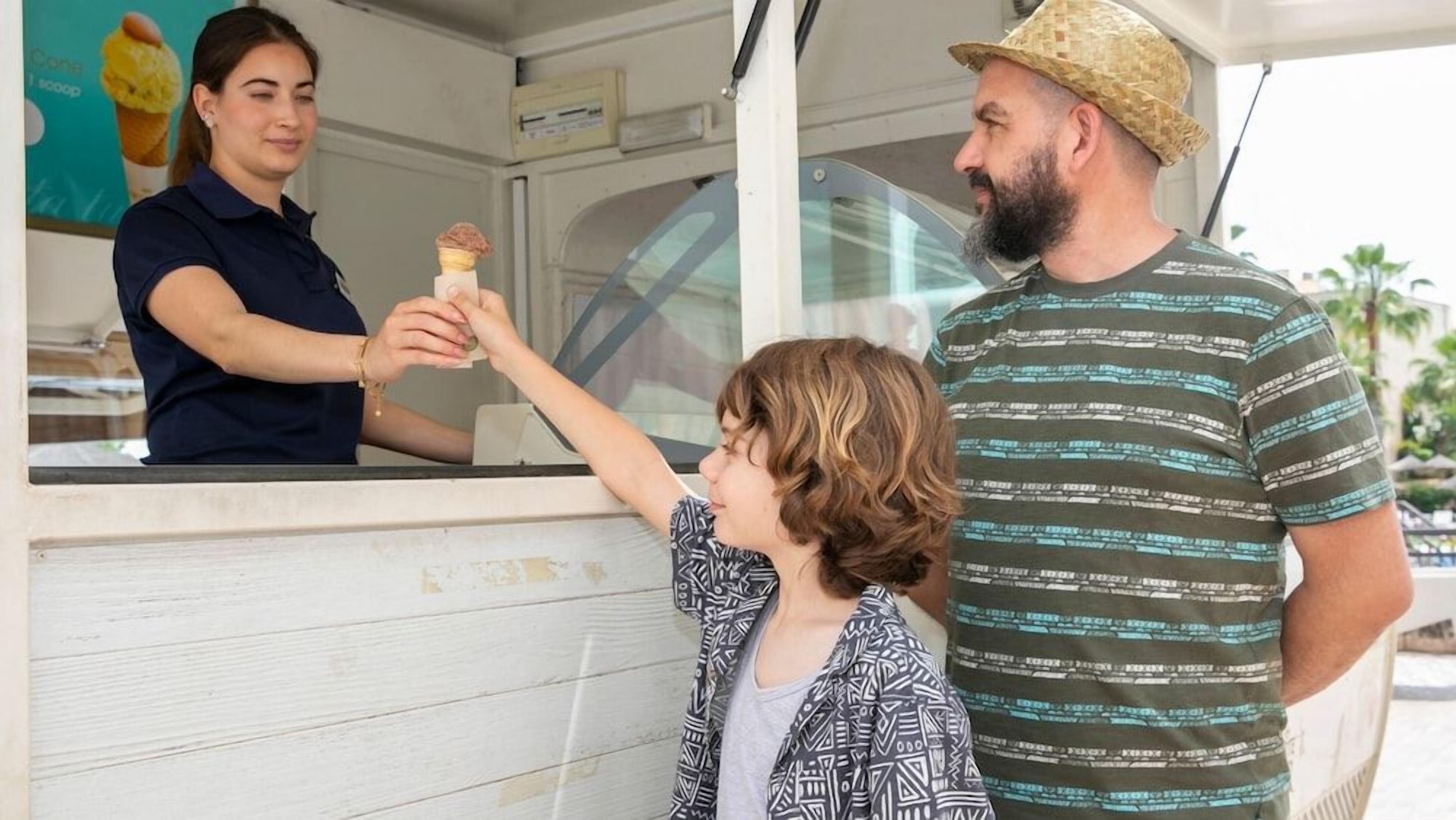 Un camión de comida donde una persona atiende a un cliente entregándole helado.