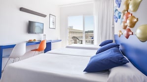A hotel room with a bed, a desk with a chair, a television, and a window with a view of buildings. - Evenia Olympic Resort - Olympic Park (Lloret de Mar)