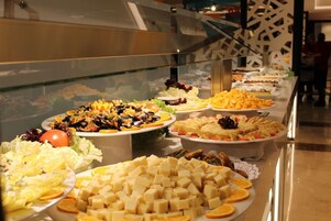 A buffet with various food items including salads, cheeses, and fruits.