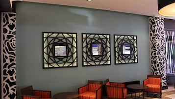 Un vestíbulo con tres obras de arte enmarcadas en la pared, una zona de estar con sillones tapizados en naranja, y un panel de pared estampado a la izquierda.