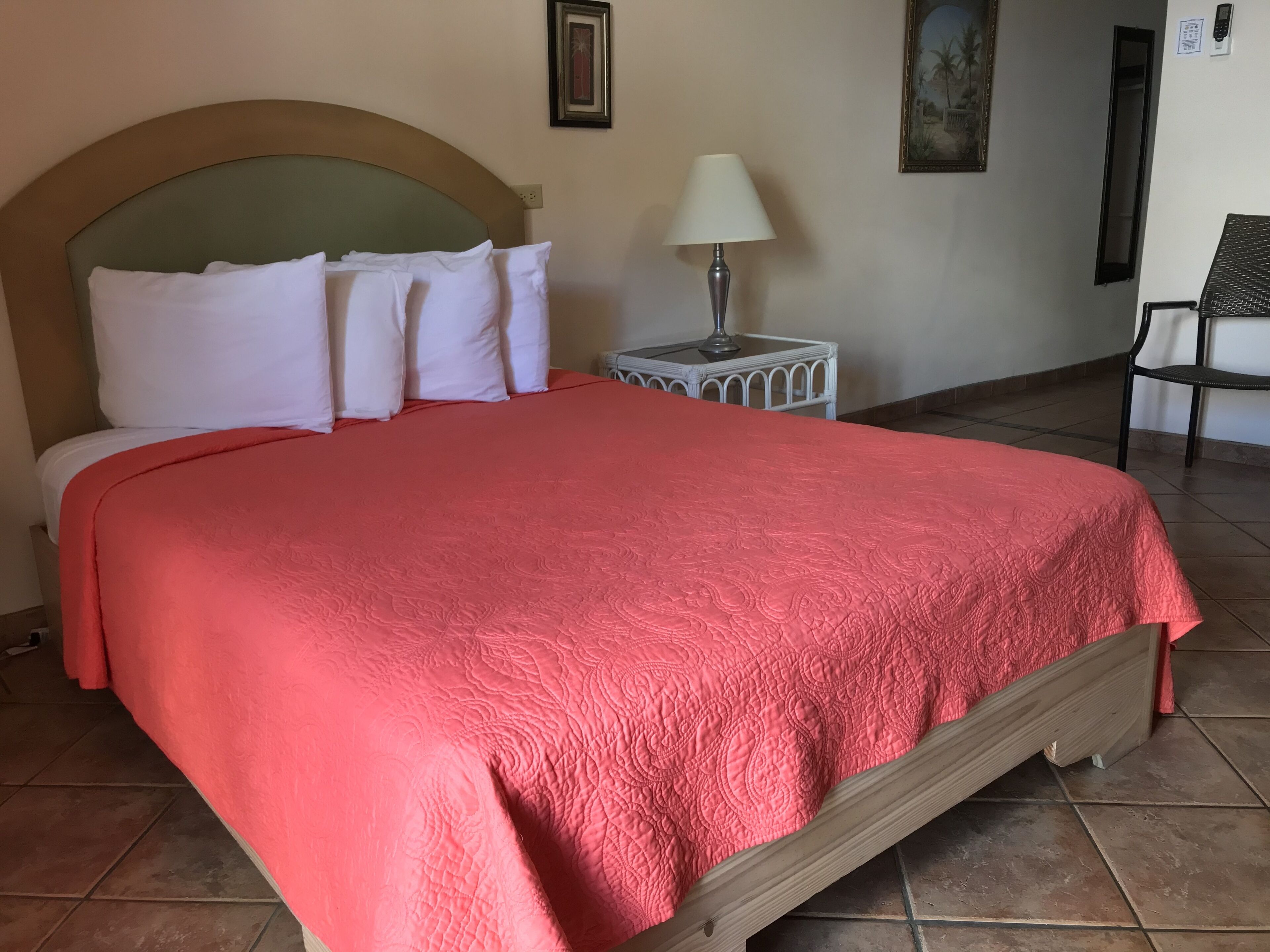 A bed with a red quilt, white pillows, and a wooden headboard.