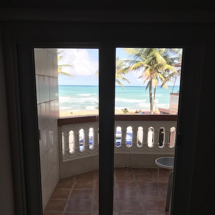 A room with a view of the beach and ocean through a glass door.